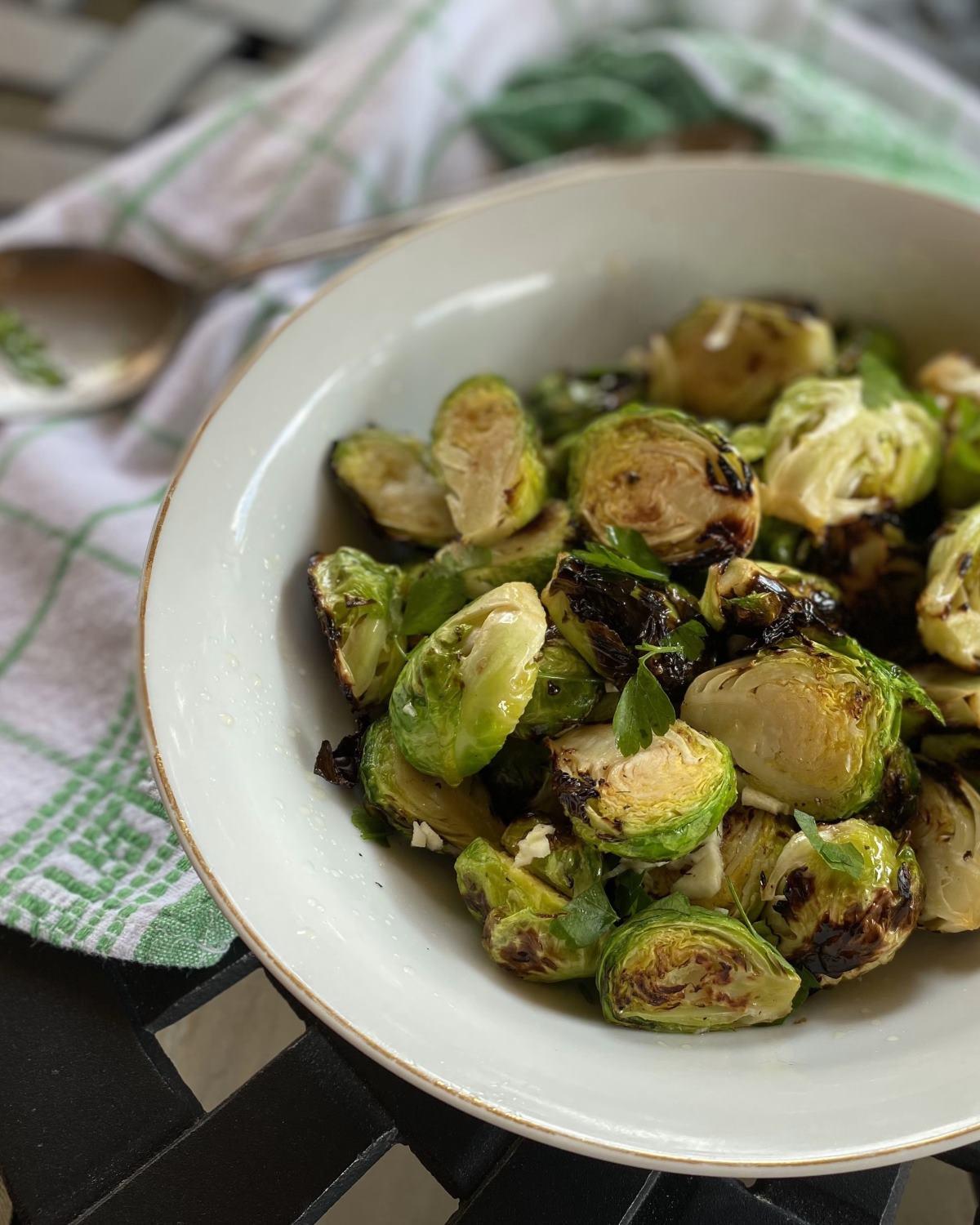 rustic wooden table with a bowl of fresh, raw Brussels sprouts, olive oil, and balsamic vinegar