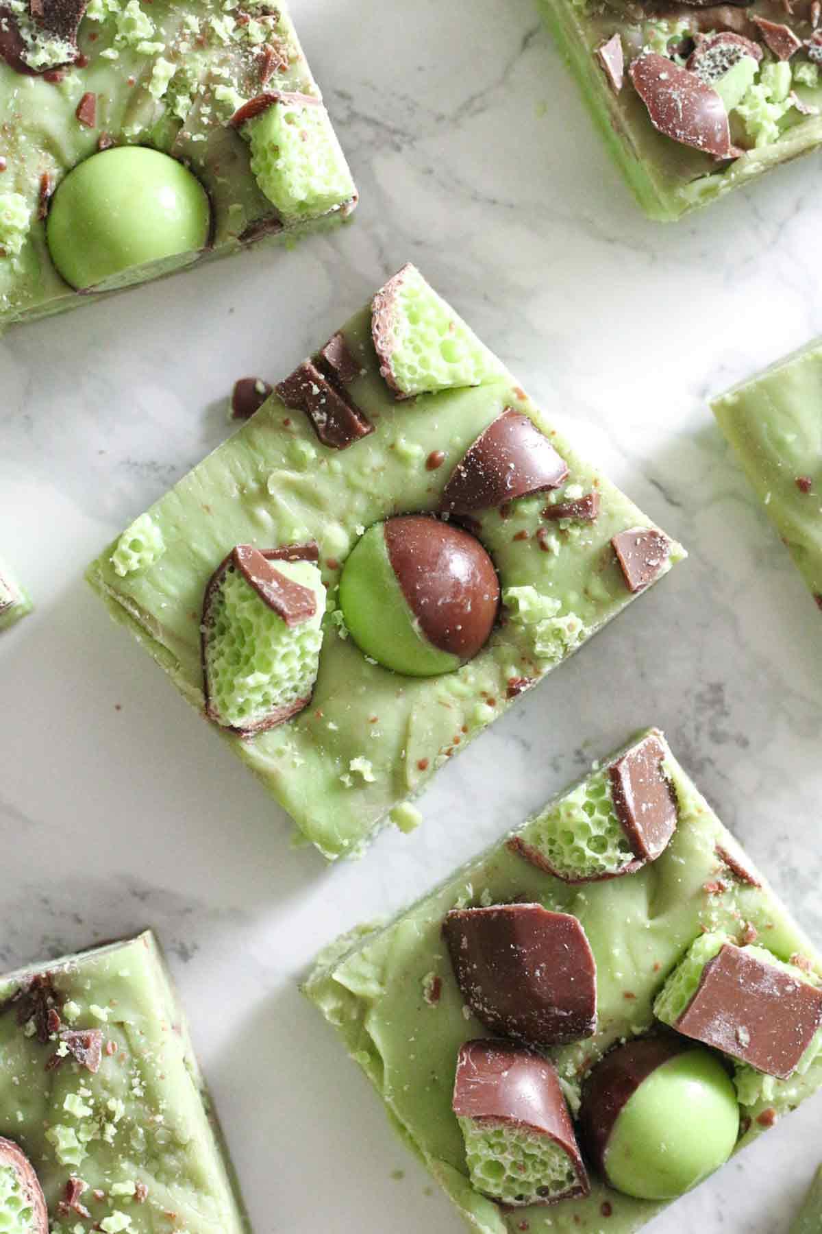 overhead shot of hands placing a fresh mint leaf on a finished tray of mint chocolate squares