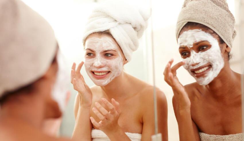 Woman applying different face masks to different areas of her face
