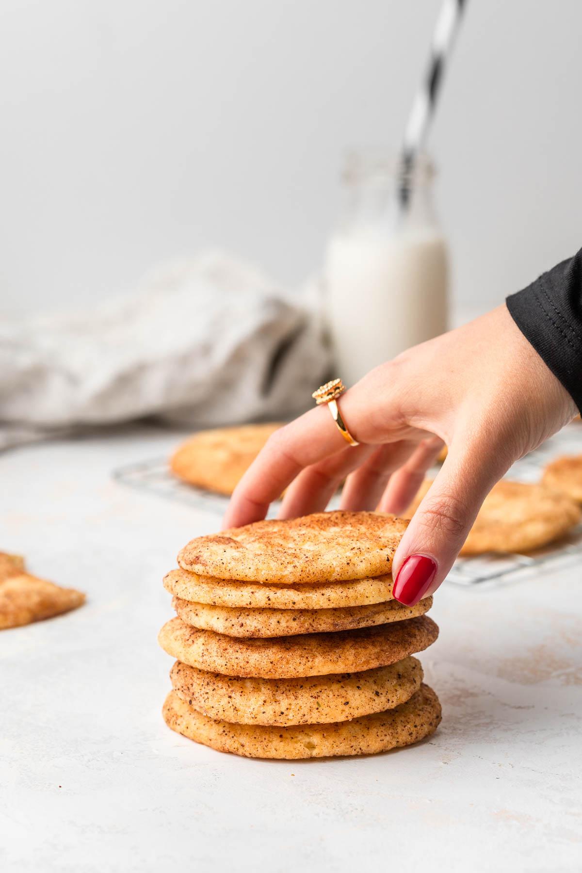 Hand reaching for a freshly baked snickerdoodle cookie