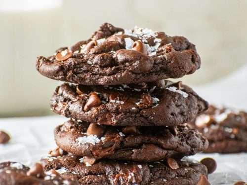 plate of freshly baked chewy double chocolate cookies, slightly warm, with a glass of milk