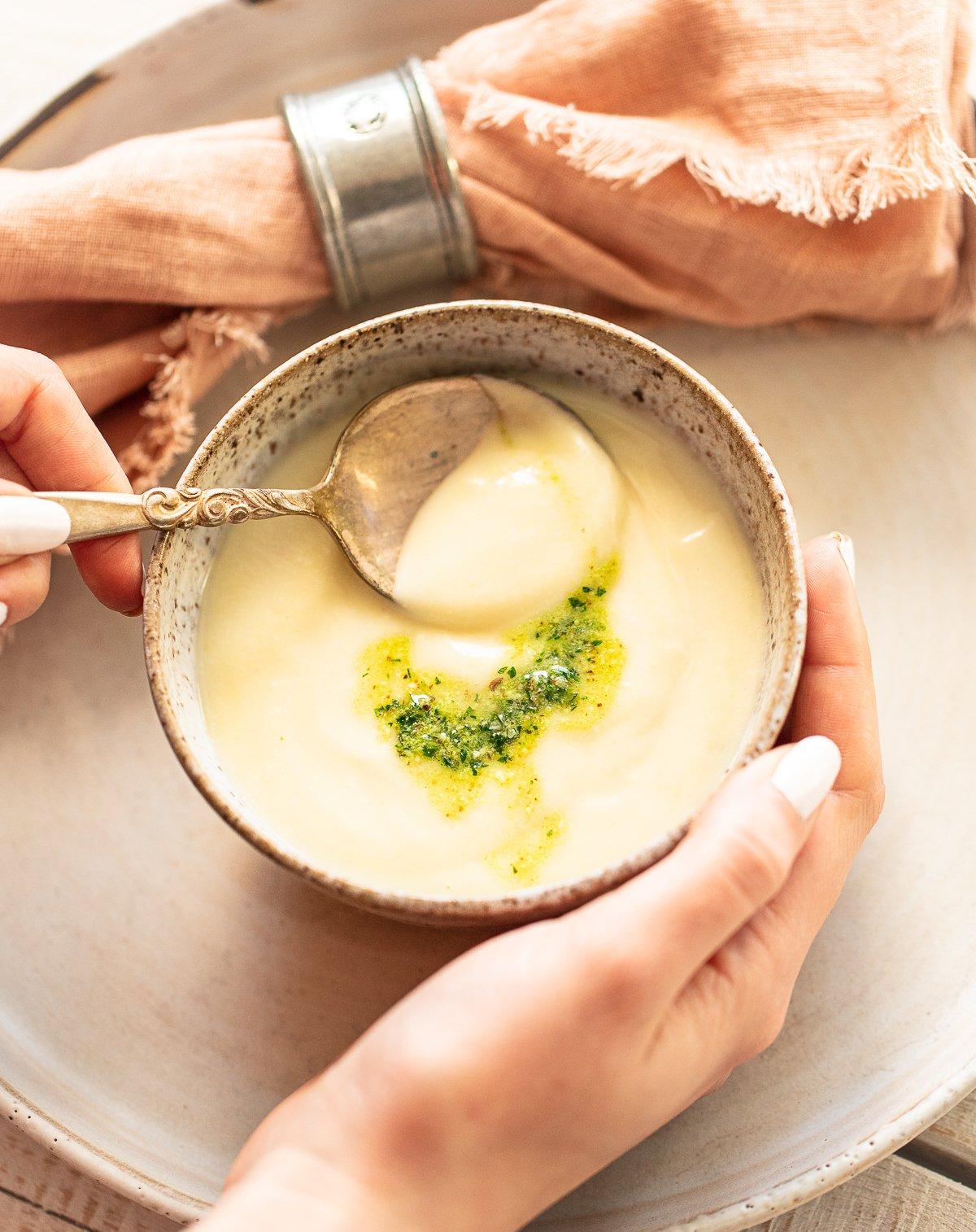 hands holding a bowl of creamy soup, cozy home setting
