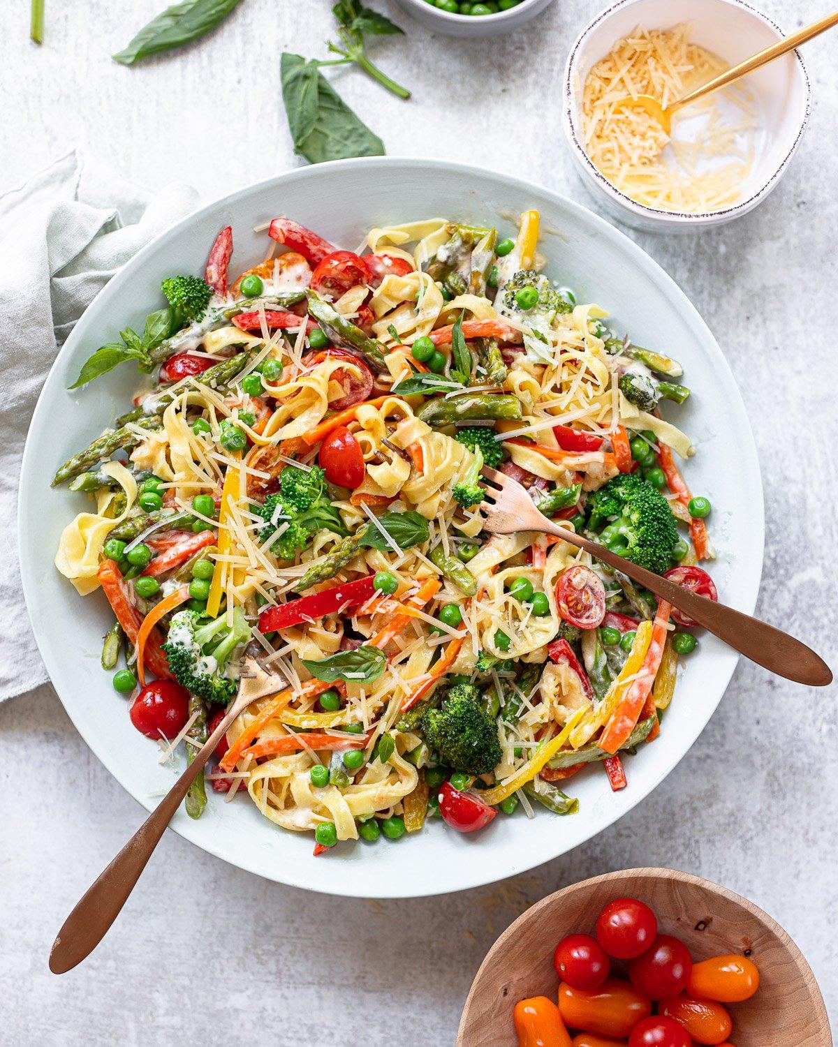Serving of one-pot pasta primavera garnished with fresh parsley and parmesan cheese