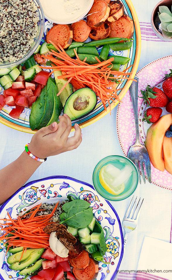 Hands holding a vibrant rainbow dinner bowl, cozy home setting