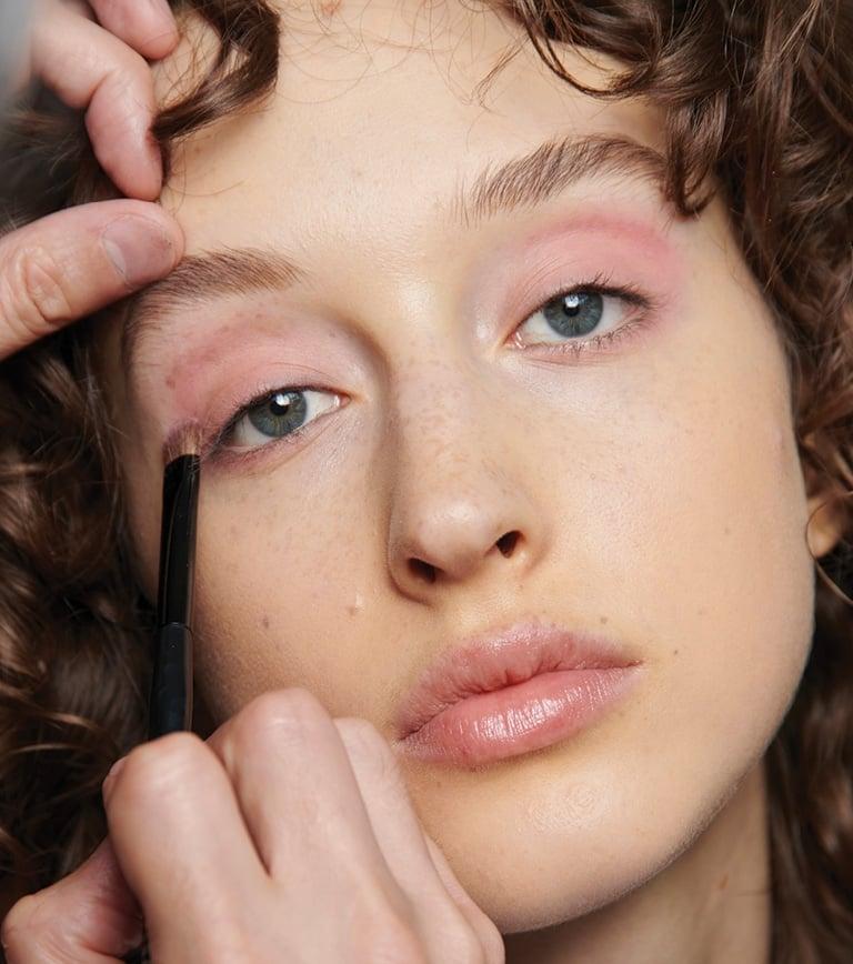 woman applying pastel eyeshadow to her eyelids