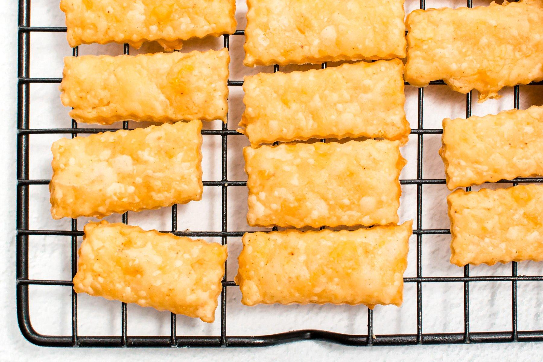 Various shaped homemade cheese crackers cooling on a wire rack
