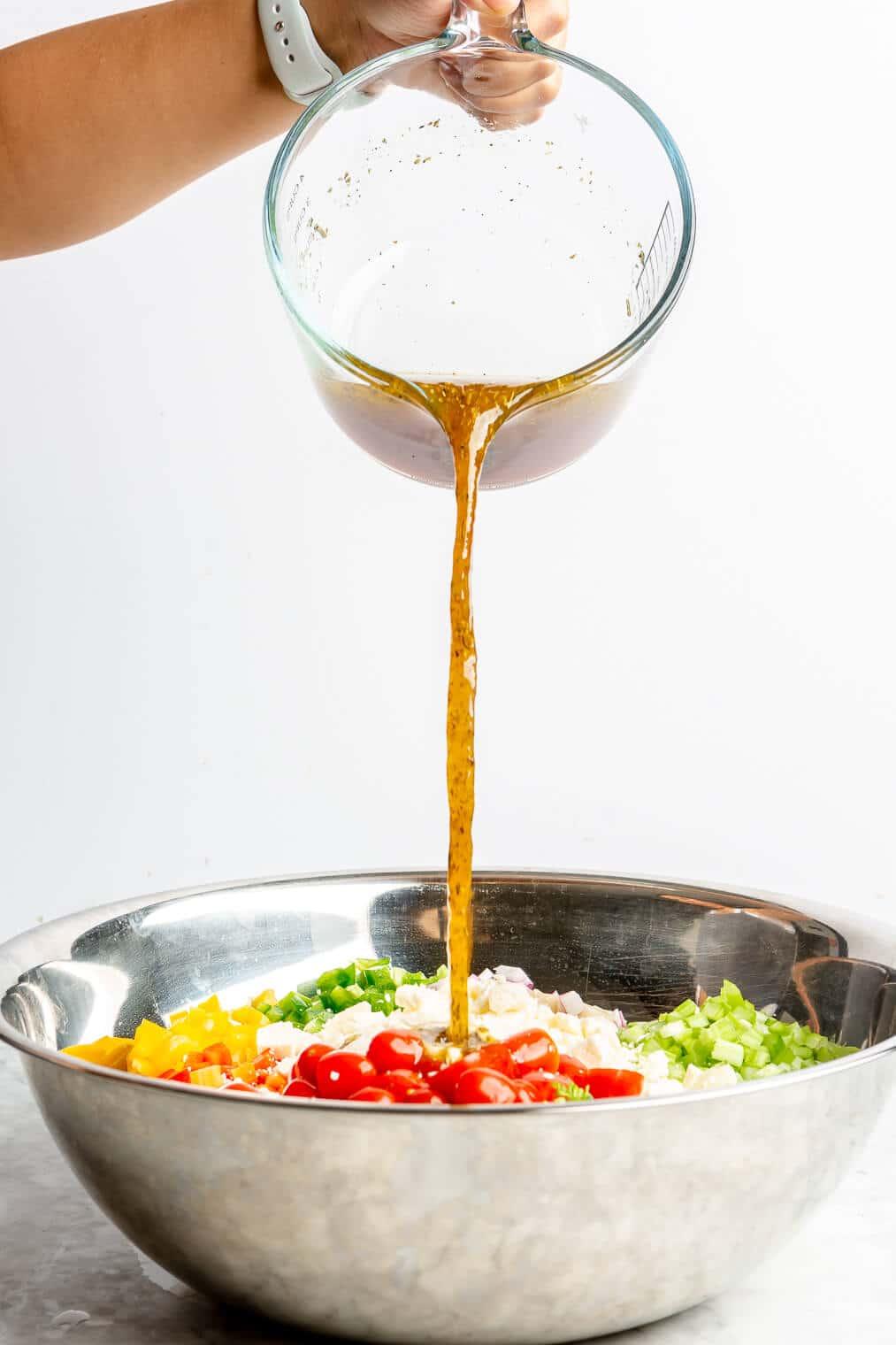 A person making pasta salad dressing in a bowl.