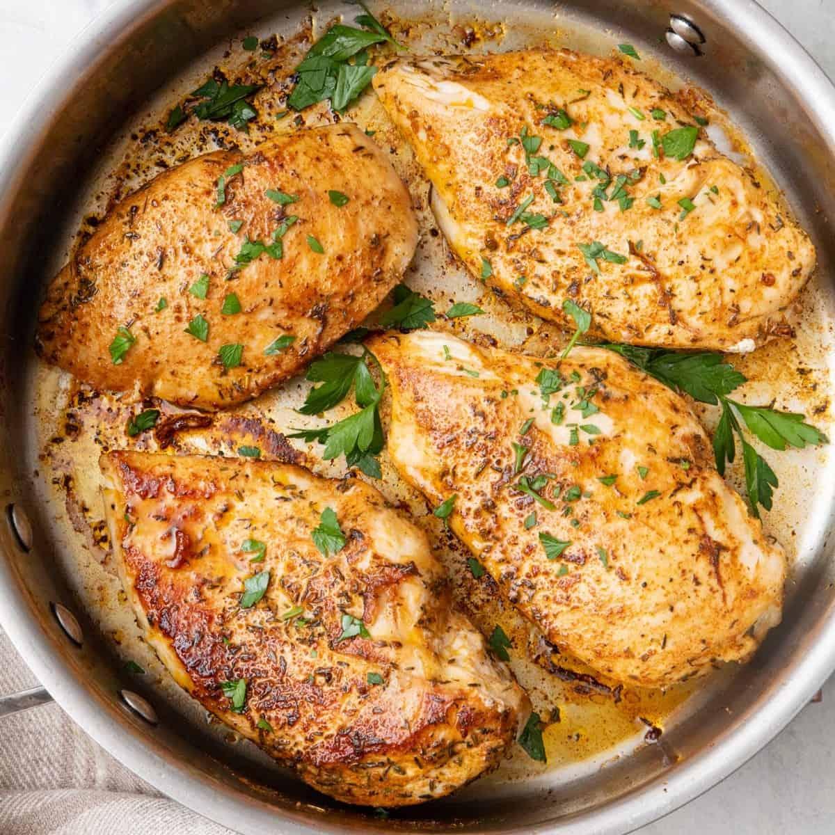 close up of perfectly pan seared juicy garlic chicken breast with herbs