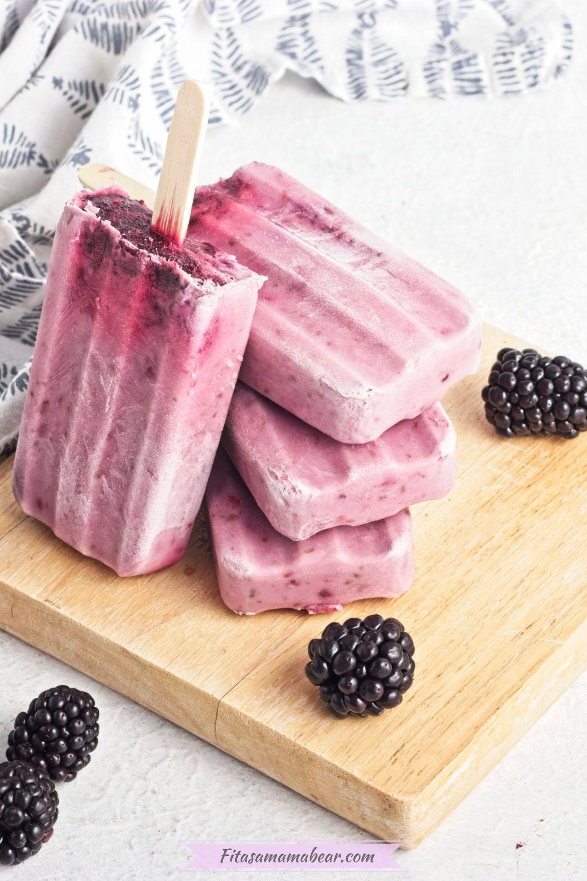 homemade black raspberry popsicles on a wooden surface