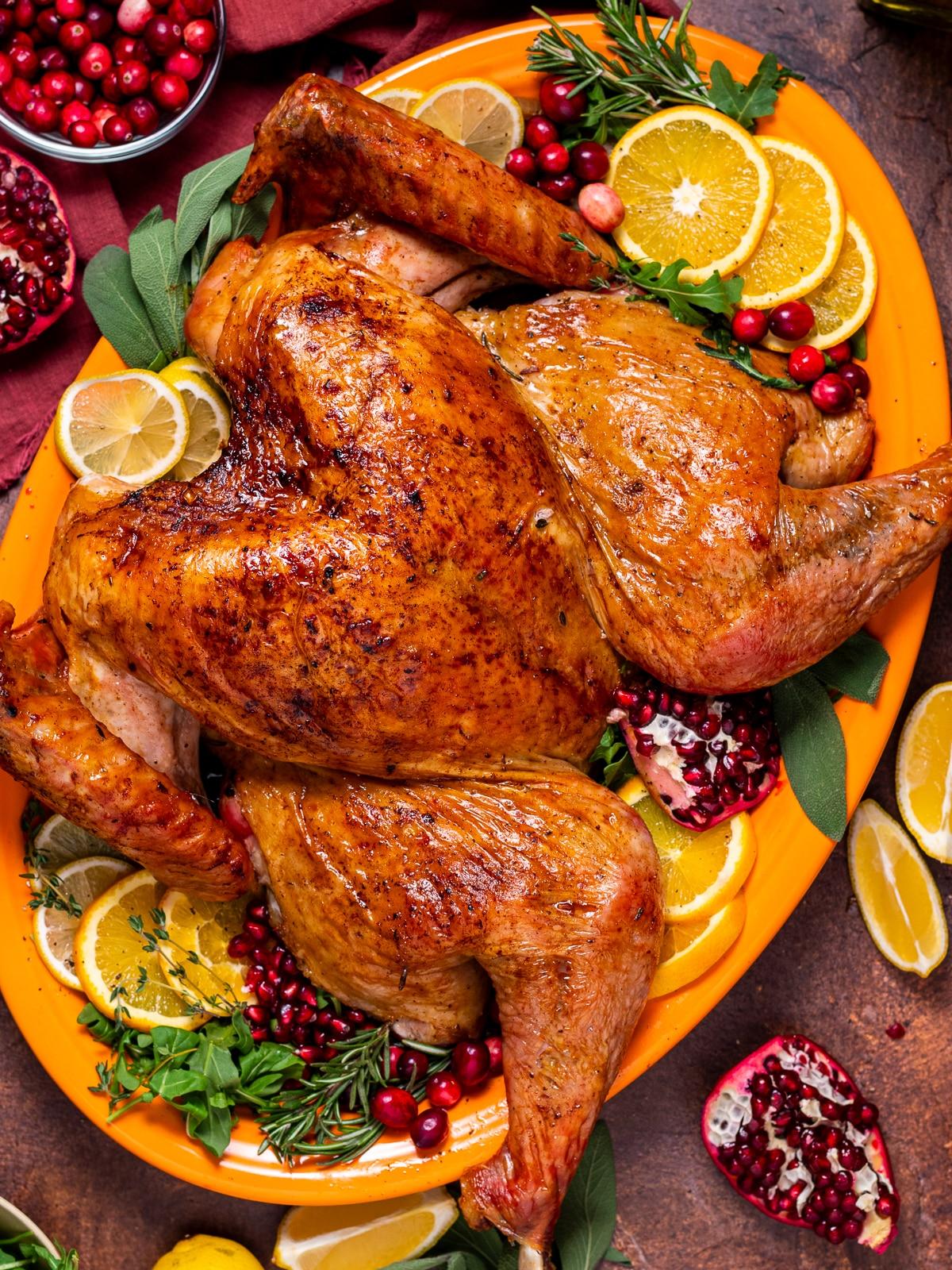 Chef's hands generously applying a pepper rub to a whole turkey, close-up
