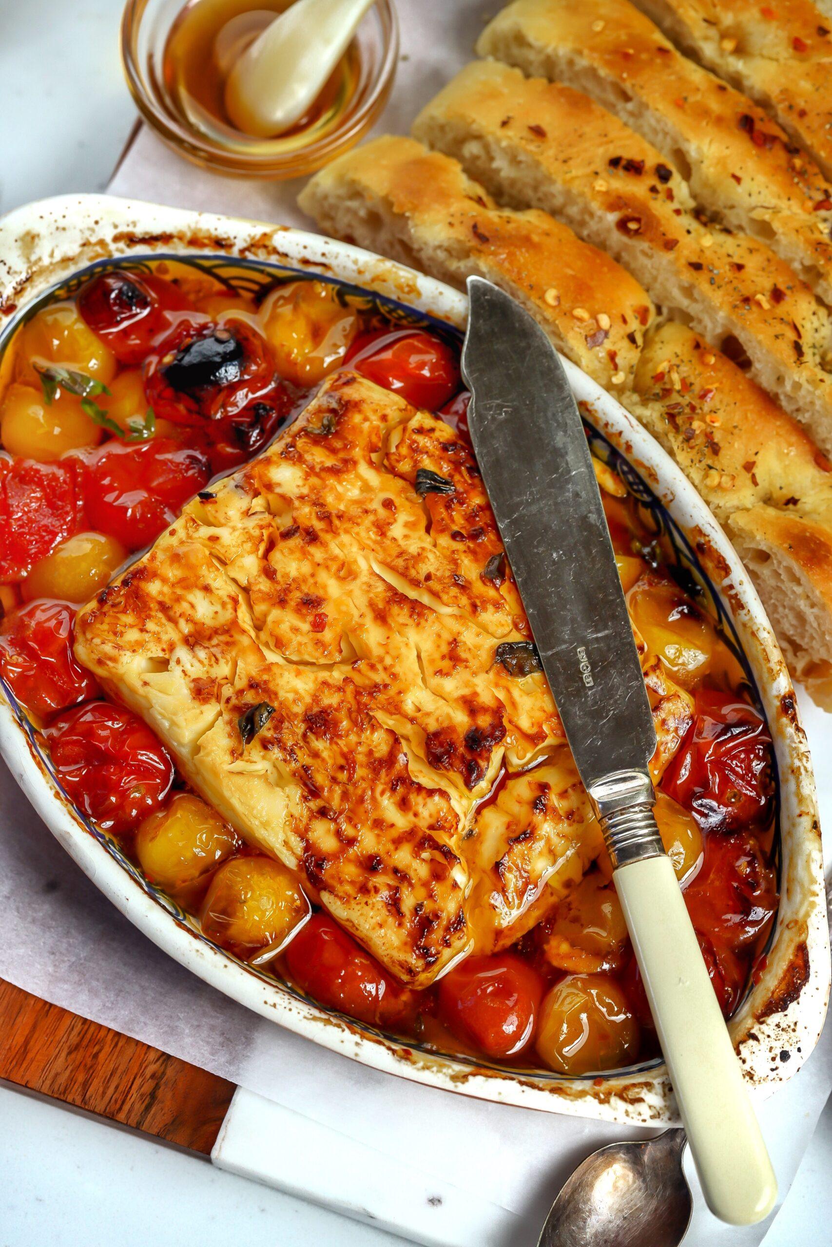 Baked feta with cherry tomatoes, fresh oregano, and crusty bread for dipping