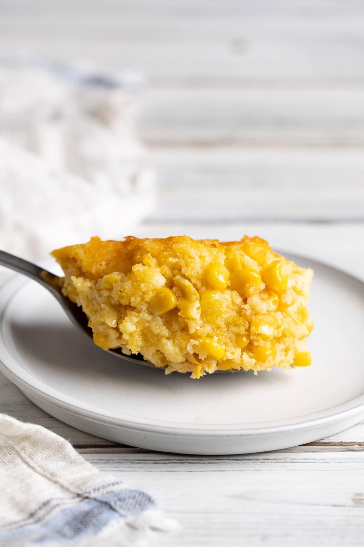 Close-up of a golden spoon scooping a fluffy spoonful of corn casserole