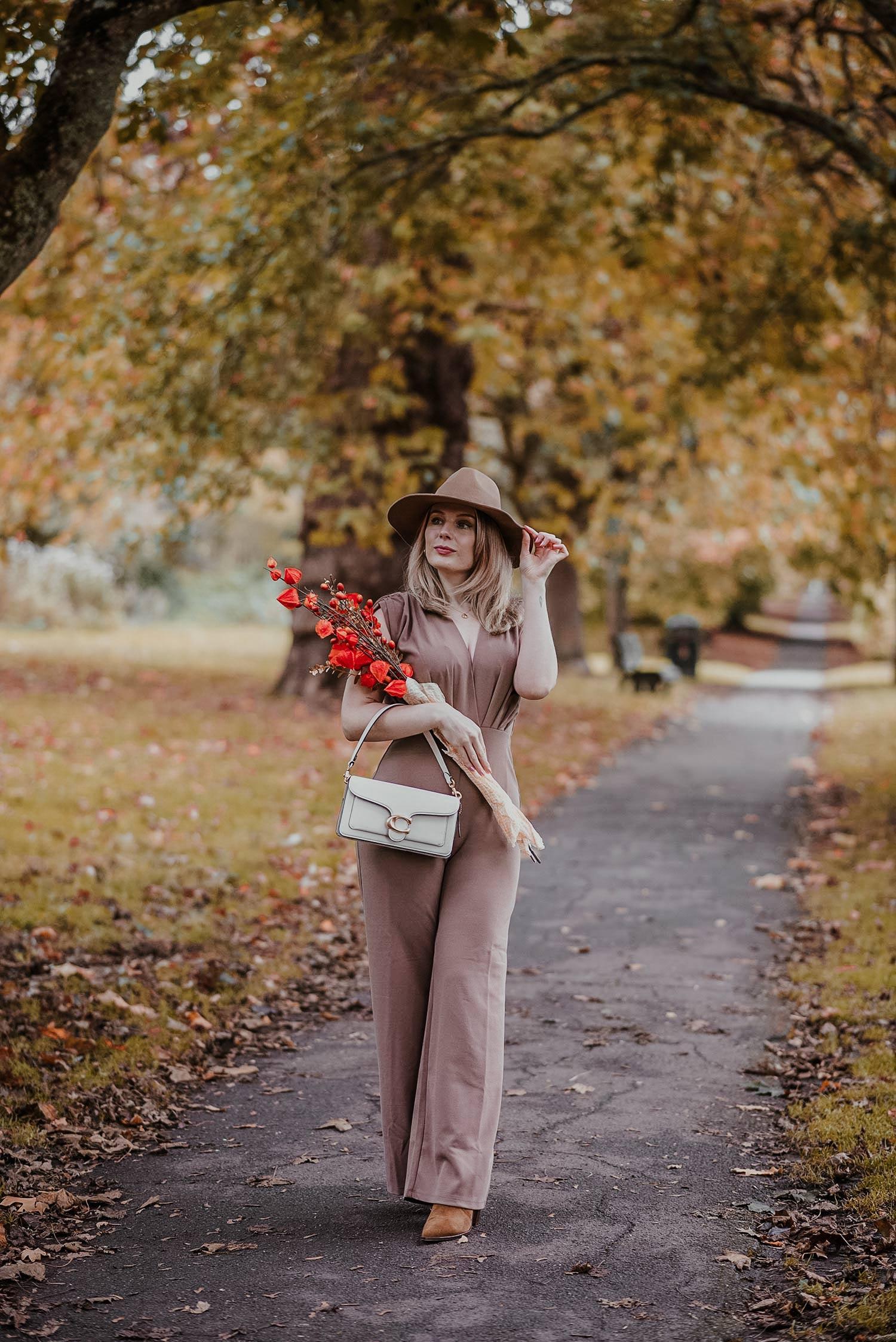 woman wearing a chic jumpsuit in a fall setting