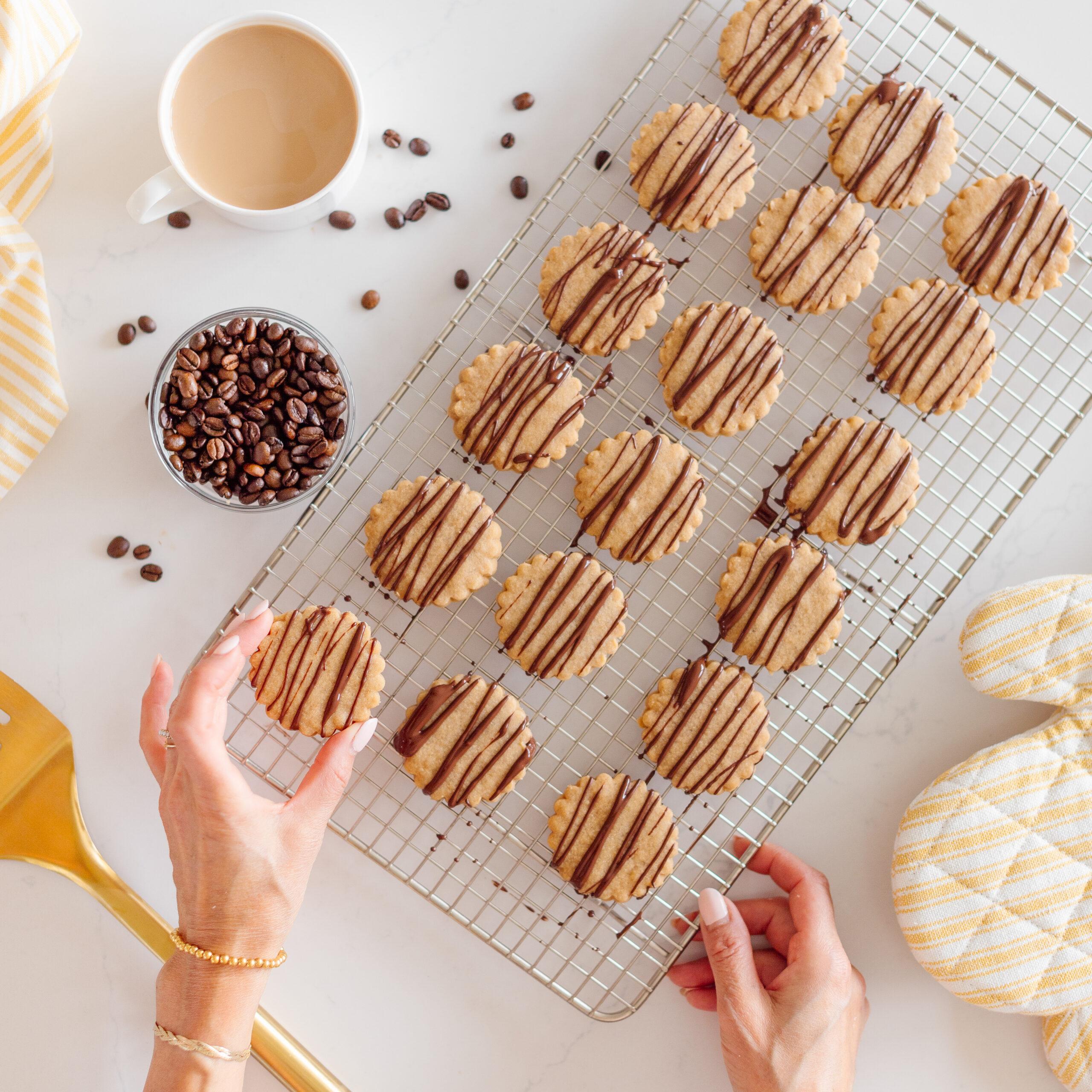 Close-up of golden brown espresso shortbread cookies on a cooling rack, steam rising from a nearby coffee cup