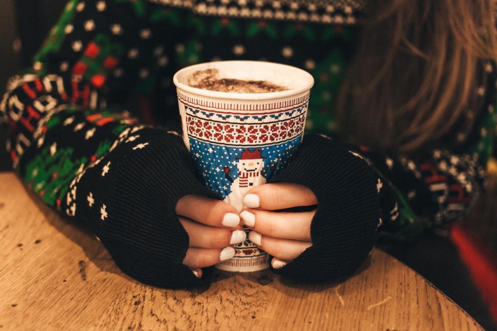 Hands holding a warm, steaming mug of truffle hot chocolate with a soft focus background