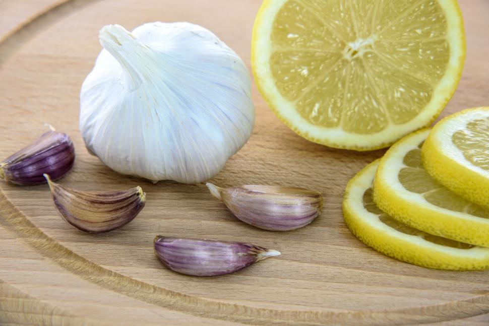 close-up shot of fresh lemons, garlic cloves, and a stick of butter on a wooden board