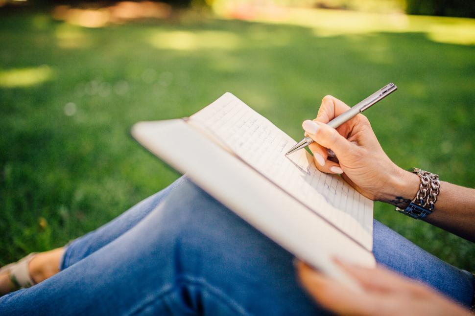 person journaling outdoors in a peaceful setting