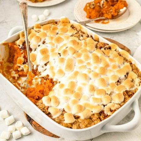 Marshmallows being carefully arranged on top of sweet potato casserole before baking