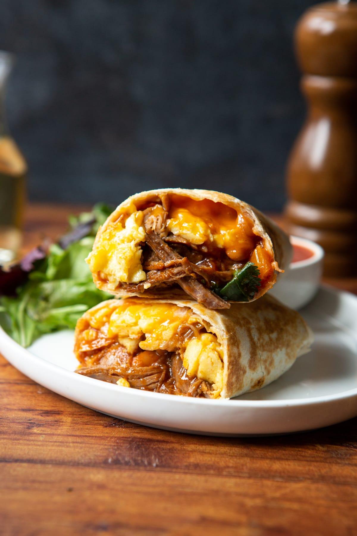A cross-section of a coffee cardamom pulled pork breakfast burrito, revealing the layers of ingredients and textures