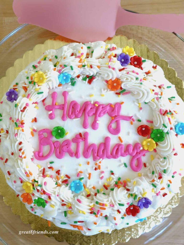 overhead shot of a beautifully frosted vanilla birthday cake on a cake stand