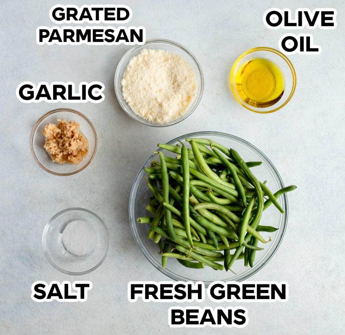 Ingredients for Green Bean Parmesan Bake laid out on a kitchen counter: fresh green beans, block of Parmesan cheese, butter, milk, garlic.