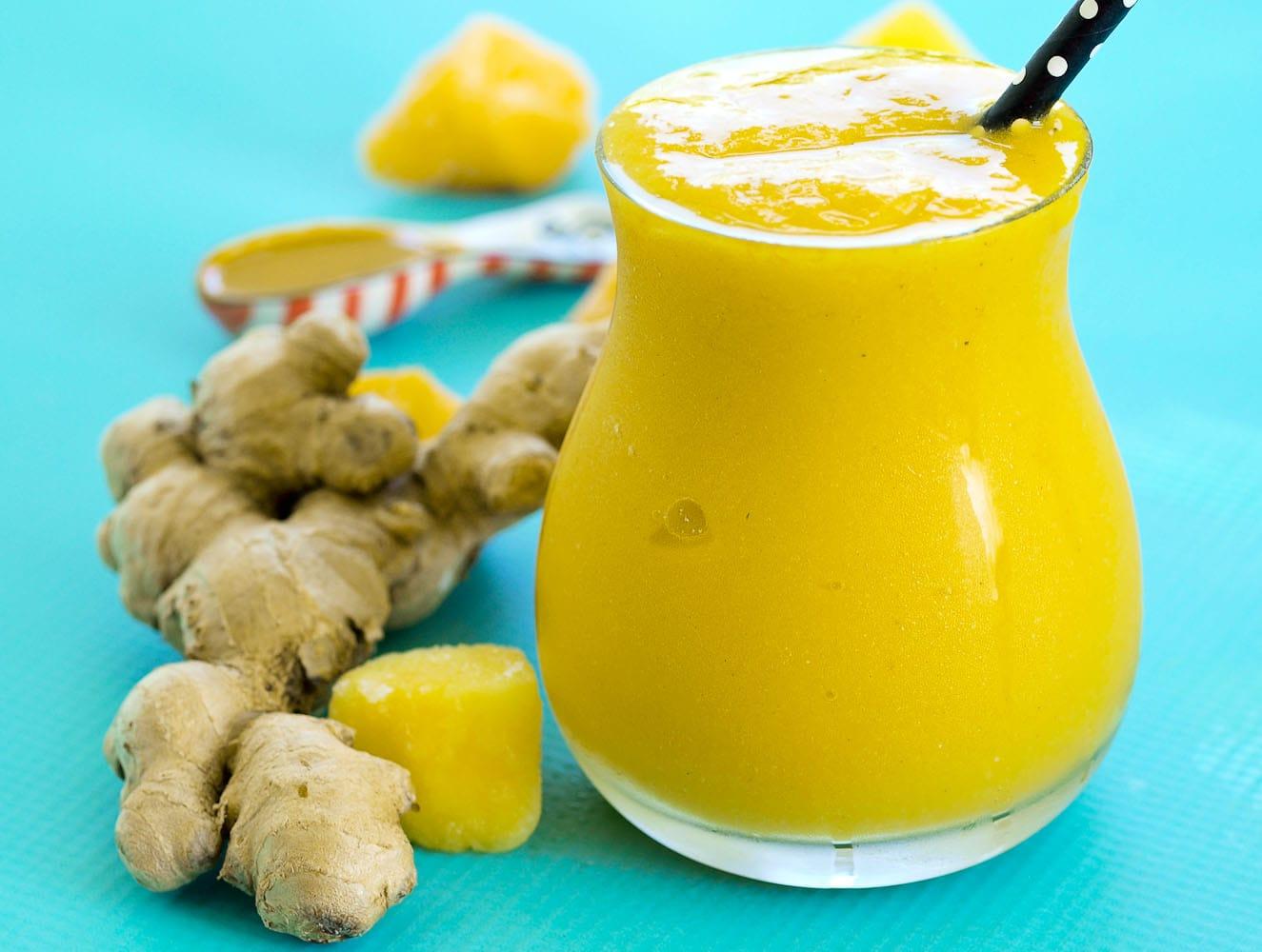 a hand adding a pinch of turmeric to a blender with smoothie ingredients