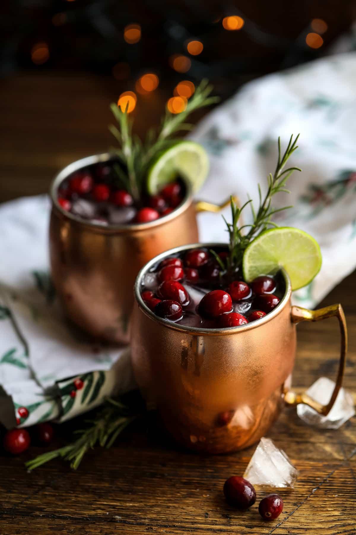 woman happily making cranberry mule cocktails in a festive kitchen