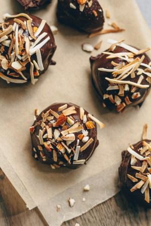 Overhead shot of a batch of finished coconut truffles on a cooling rack, with some drizzled with dark chocolate