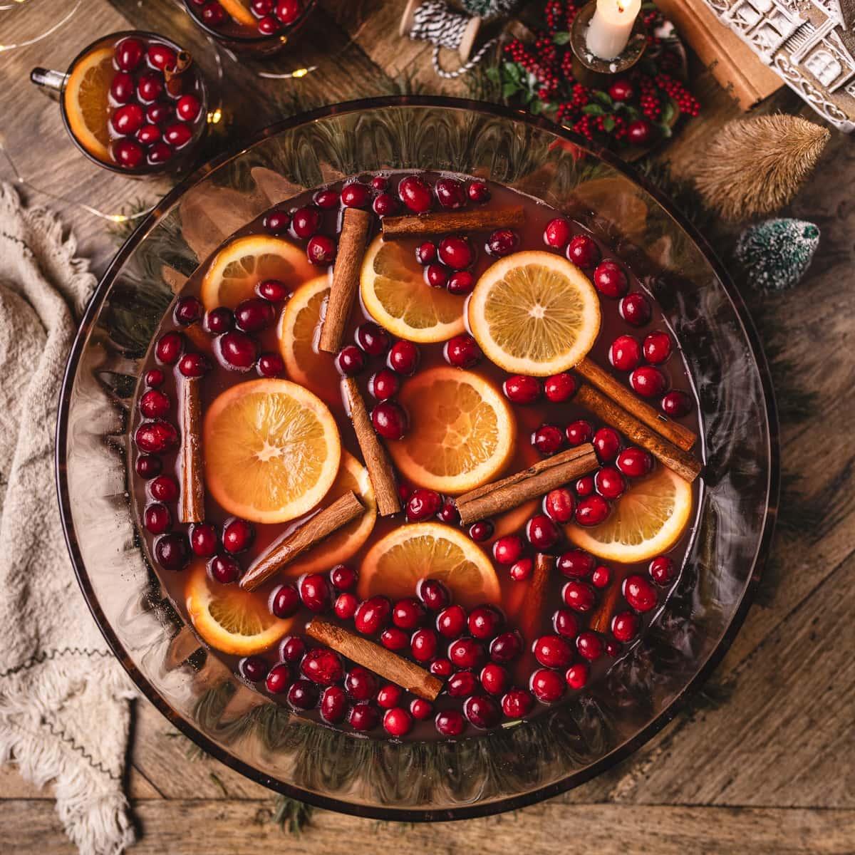 Delicious festive orange clove punch with cinnamon sticks and orange slices, steaming, in a holiday setting