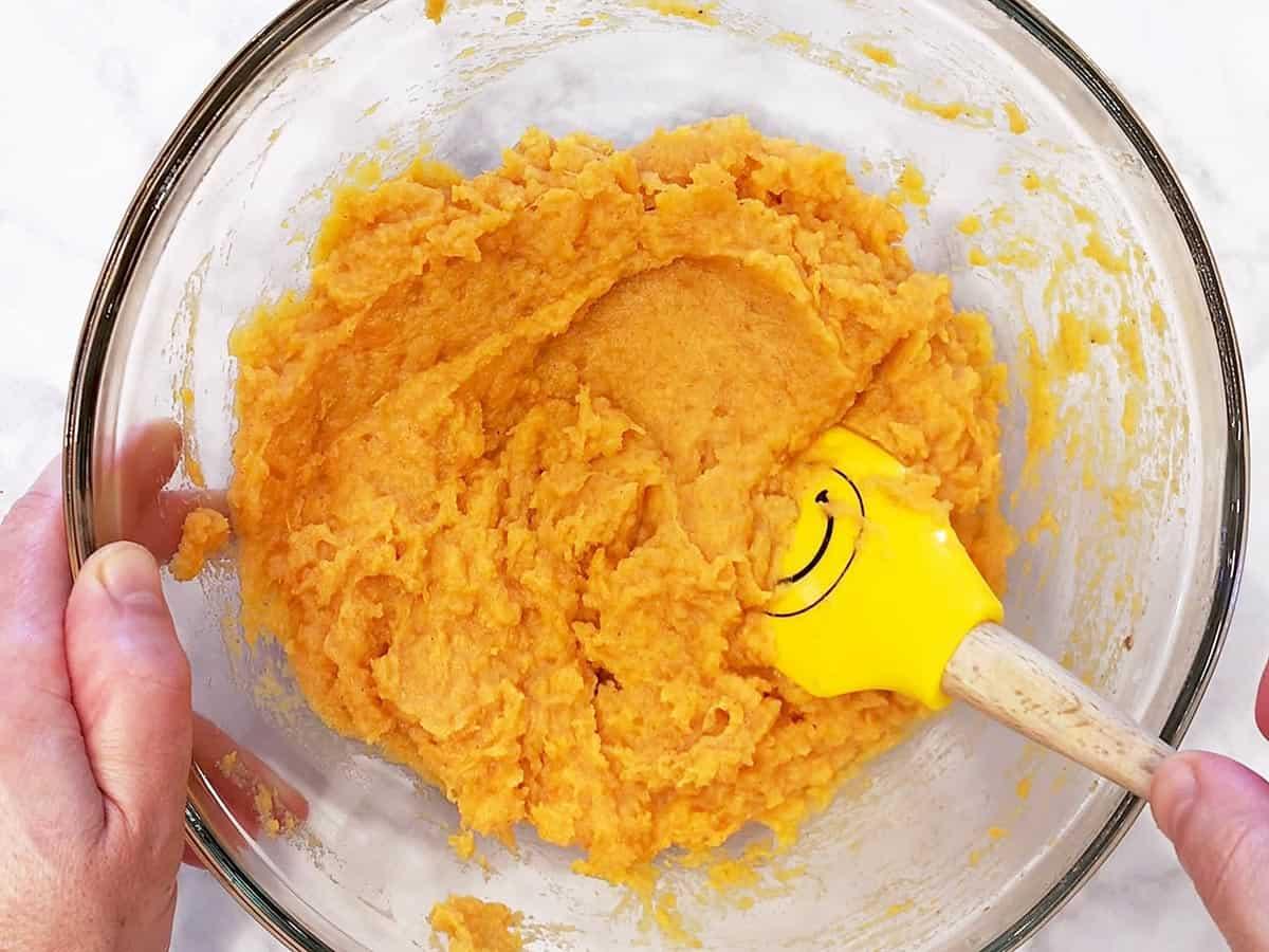 Creamy mashed sweet potato mixture in a mixing bowl with a spatula