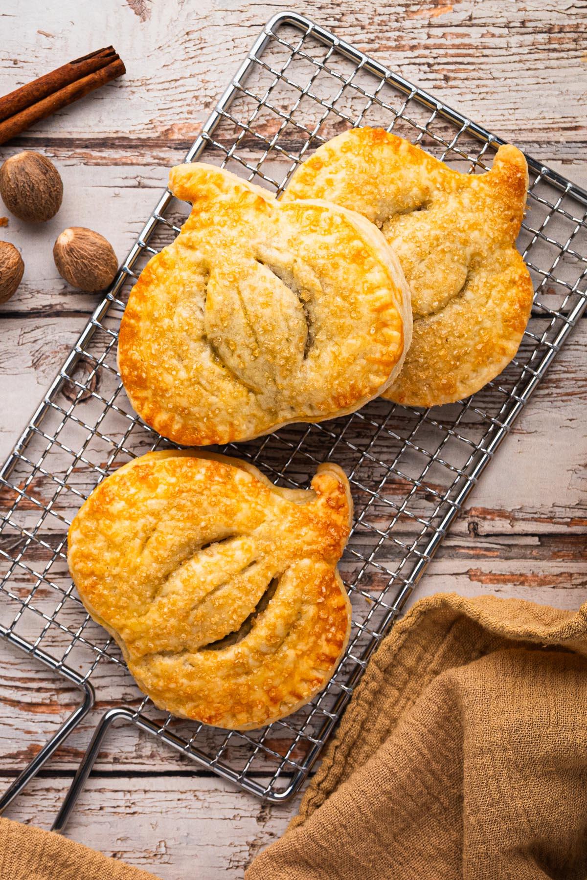 Hands gently placing a homemade pumpkin pie onto a cooling rack
