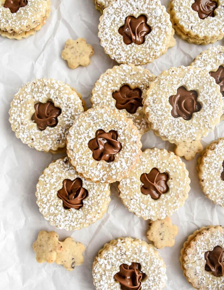 Close-up of raw cookie dough studded with finely ground hazelnuts on parchment paper.