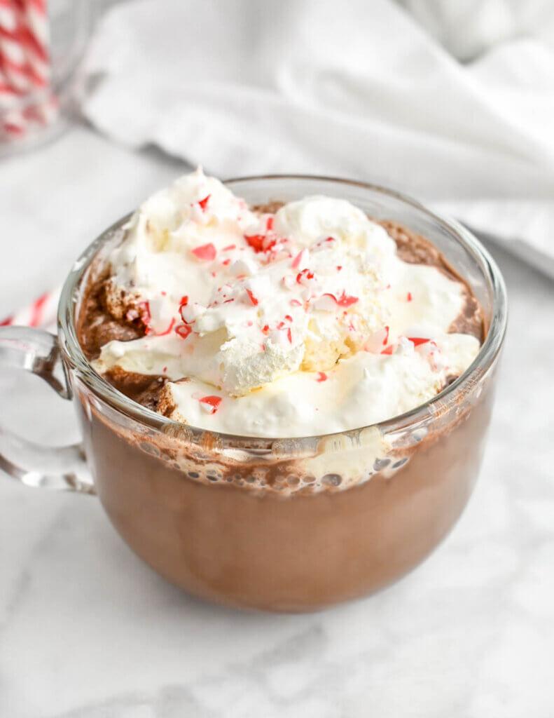 Close-up of a festive peppermint mocha in a mug, garnished with whipped cream and crushed candy canes