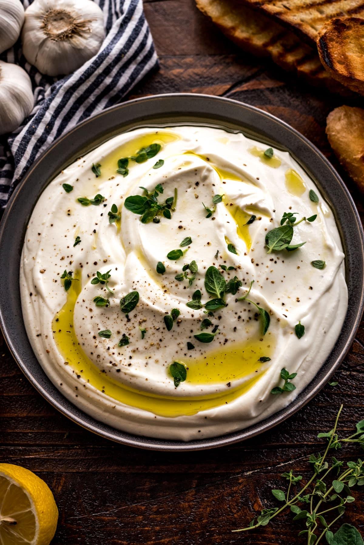 creamy whipped ricotta in a bowl with a lemon half and olive oil next to it