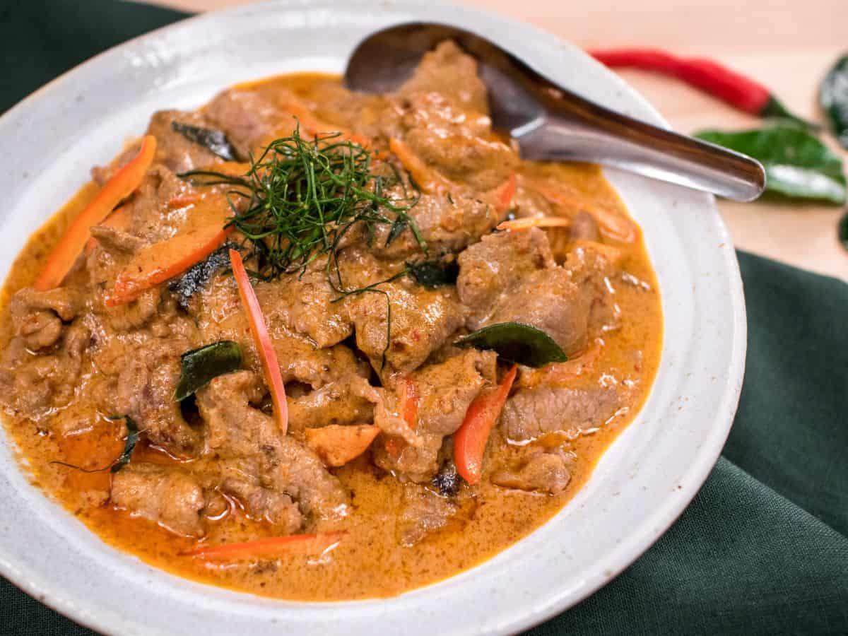 Panang curry beef with coconut milk, garnished with Thai basil and red pepper