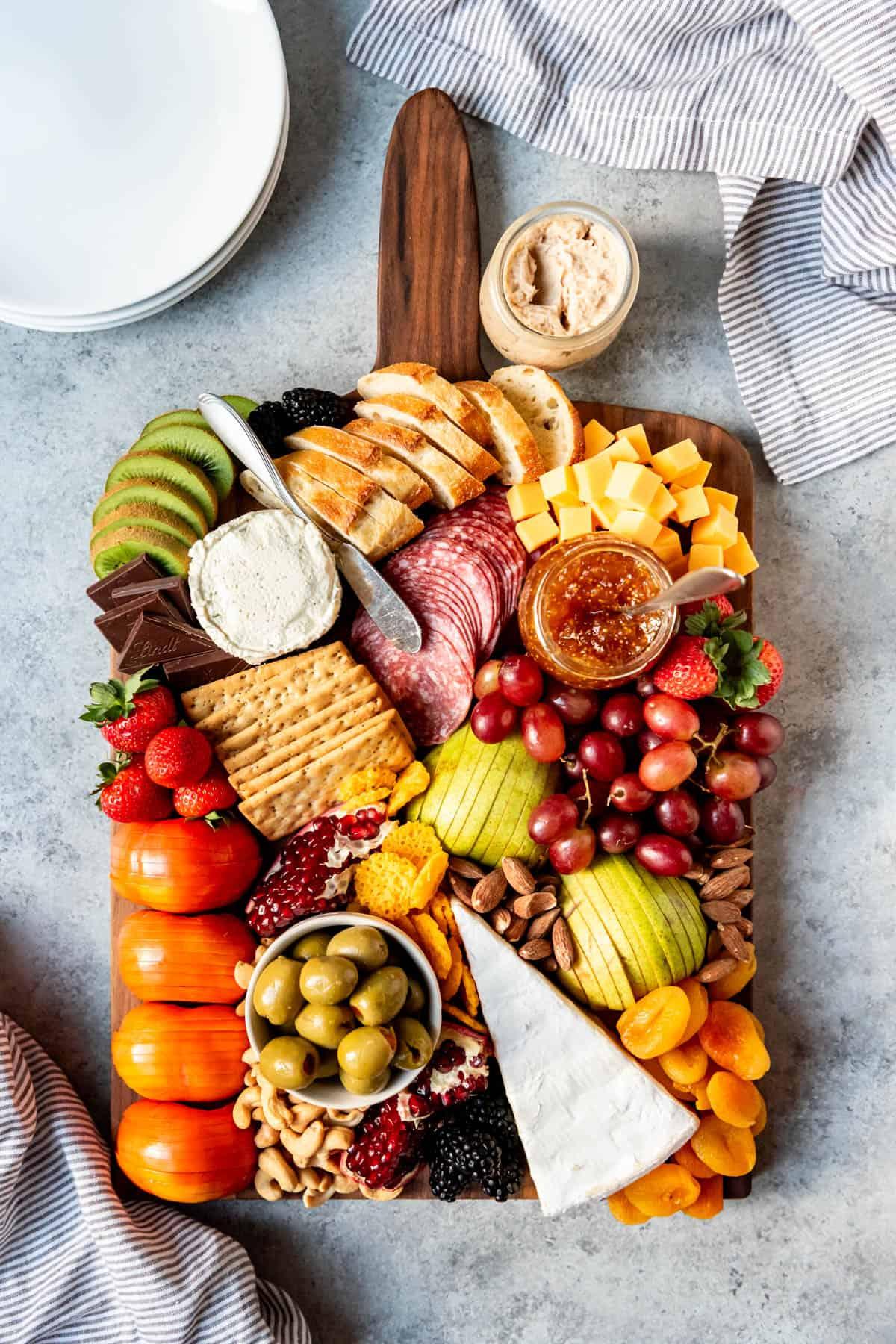 Elegant charcuterie board with honeycomb, various cheeses including brie, cured meats, fresh fruit, nuts, and crackers on a wooden surface.