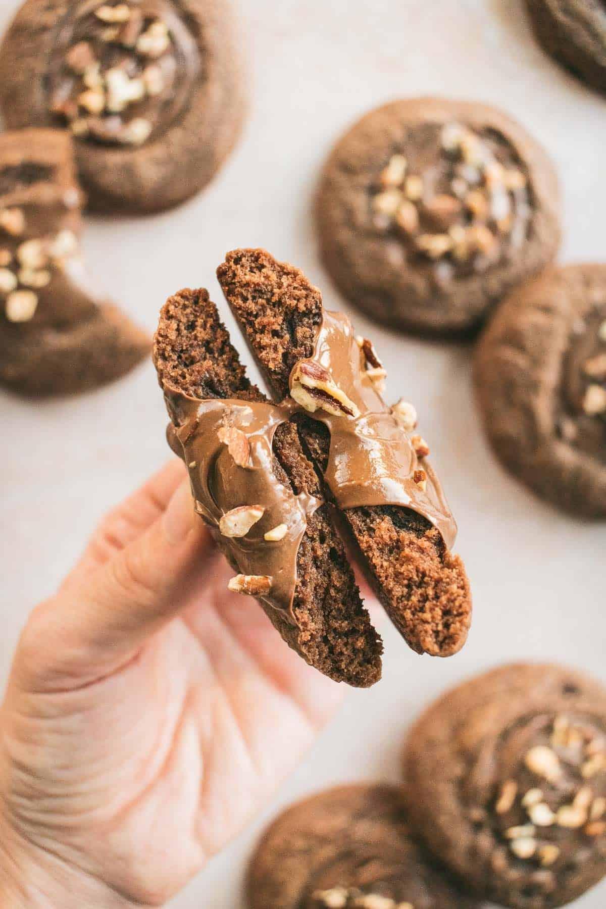 Hands holding a warm chocolate thumbprint cookie, steam rising lightly
