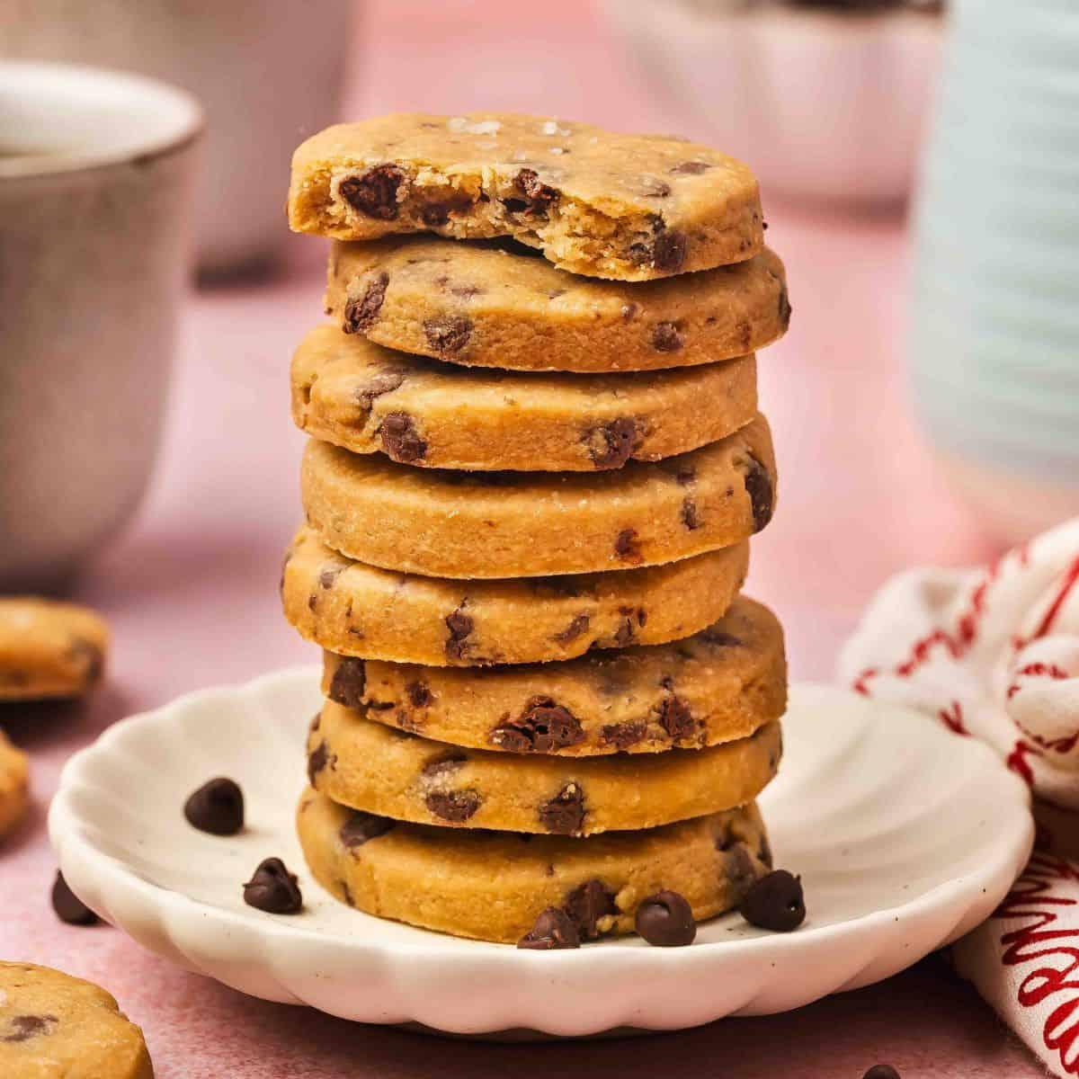 Hand dipping an espresso shortbread cookie into a white ceramic mug of freshly brewed coffee, cozy background