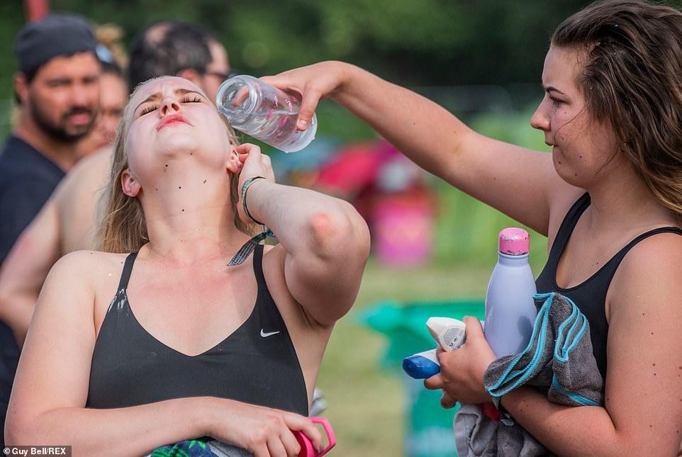 girl helping another girl open a water bottle at a music festival