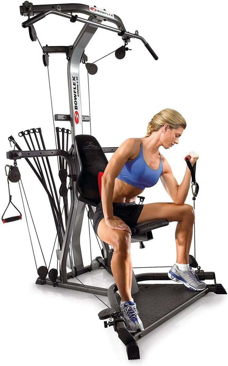 A woman assembling a Bowflex Xtreme 2 SE Home Gym, looking slightly puzzled