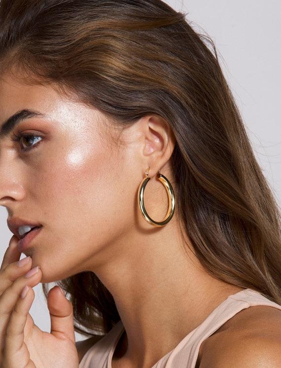 Woman wearing oversized gold hoop earrings