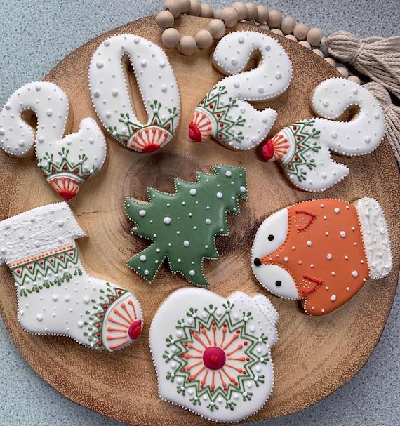 Various gingerbread cookies, some plain and some intricately decorated with white and colored royal icing, arranged on a rustic wooden board