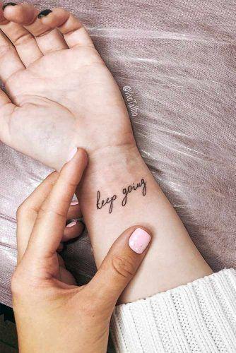 woman admiring her small wrist tattoo