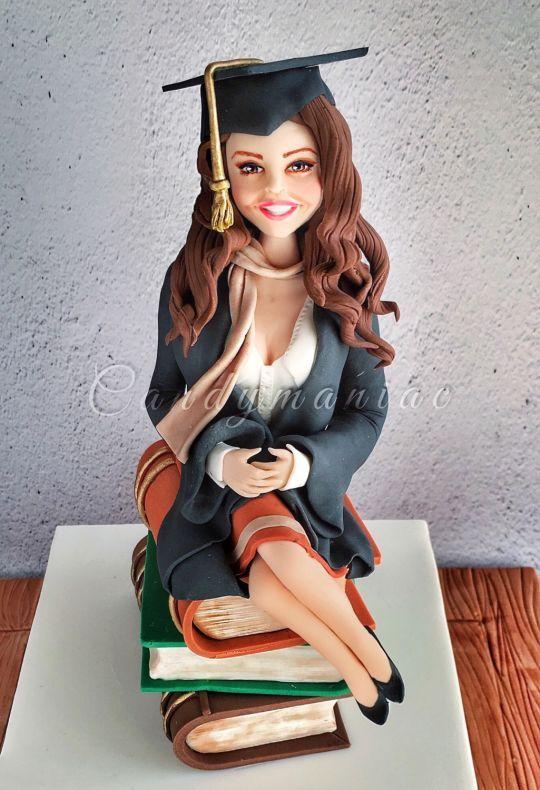 a graduate smiling while holding a slice of graduation cake