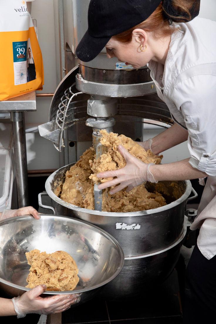 person mixing cookie dough in a kitchen setting with a warm ambiance