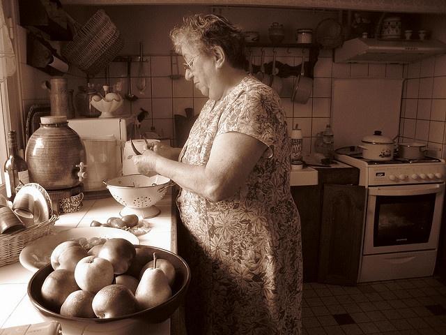 Vintage style photograph of a grandmother cooking in a kitchen, warm lighting