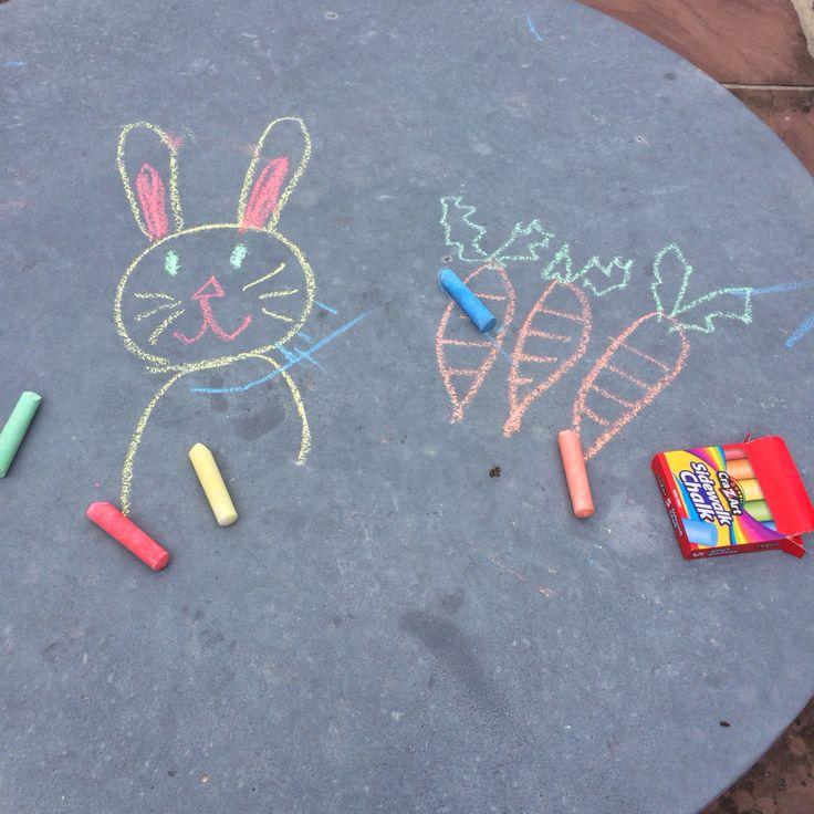 children drawing easter art on a chalkboard outside