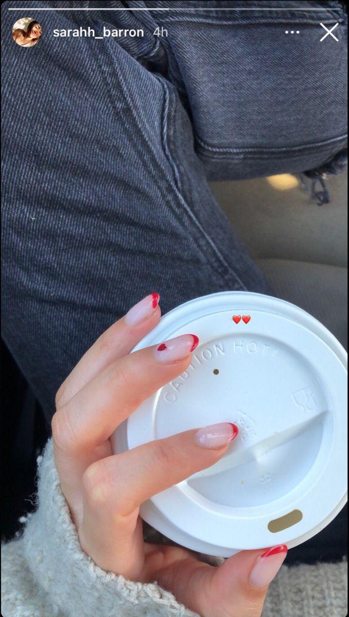 woman confidently showing off her almond-shaped nails while holding a coffee cup in a trendy cafe, reflecting a sense of style and self-assurance