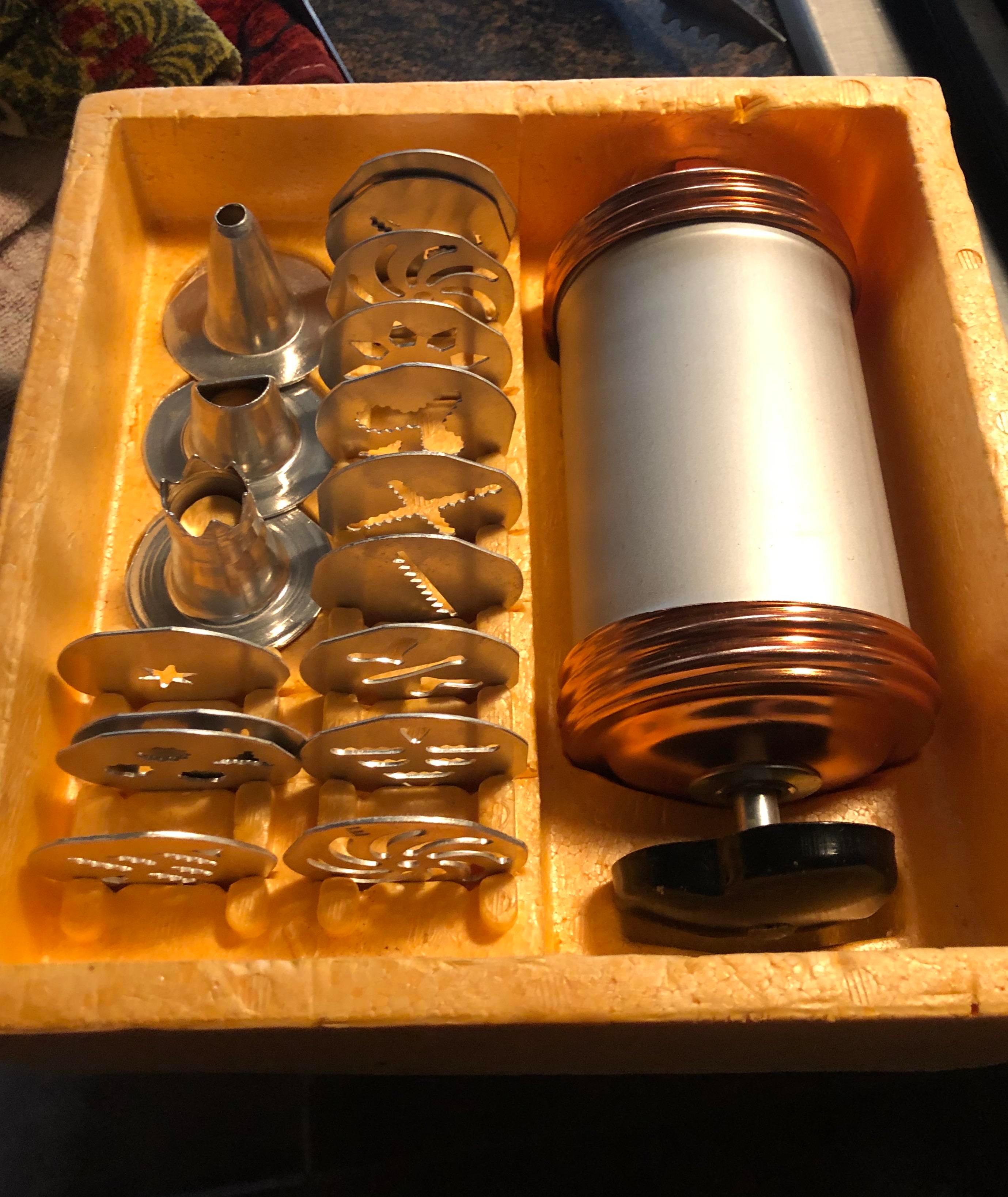 Vintage cookie press in action, extruding dough into a festive shape