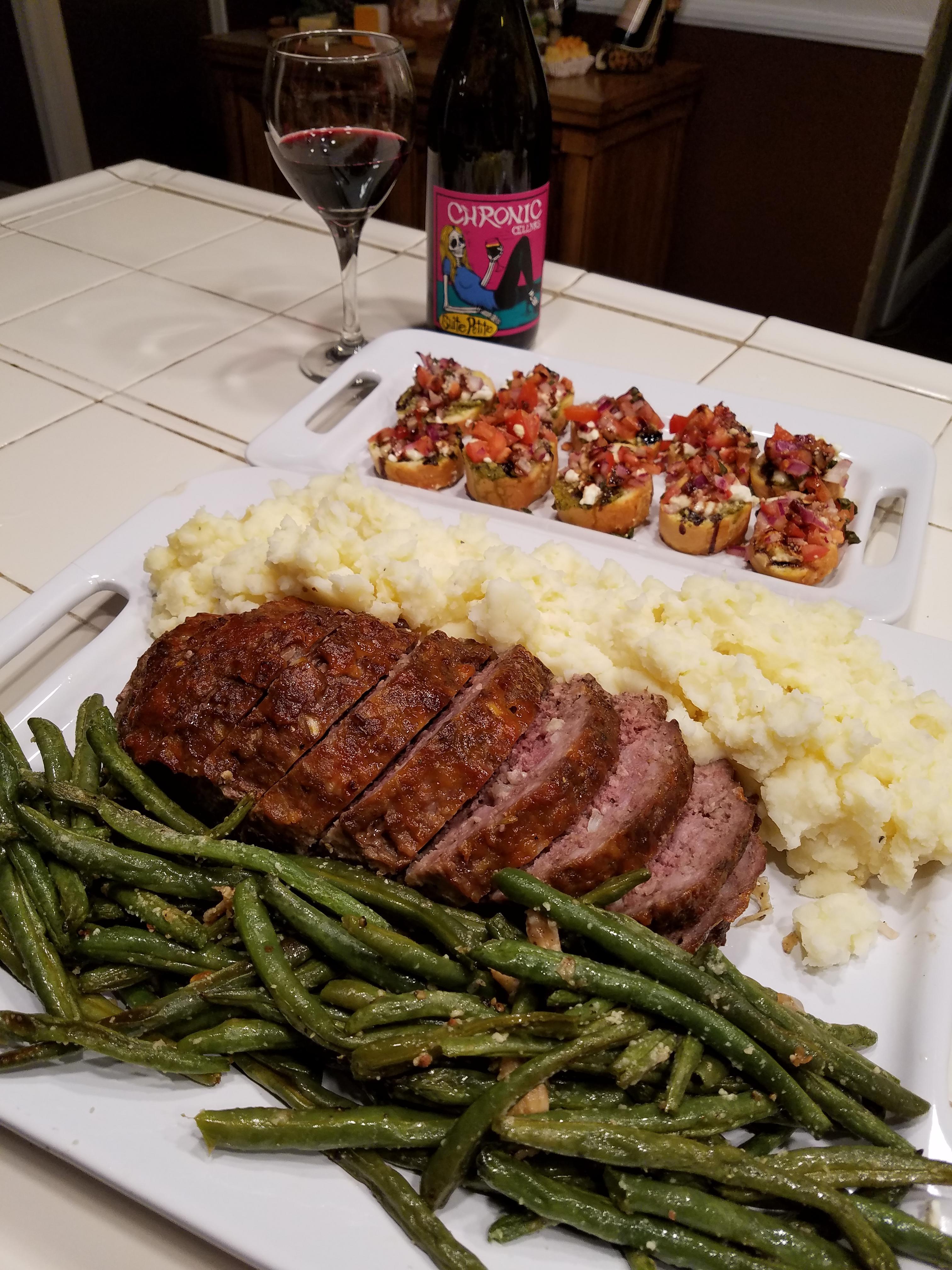 table setting with meatloaf, mashed potatoes, green beans, and gravy
